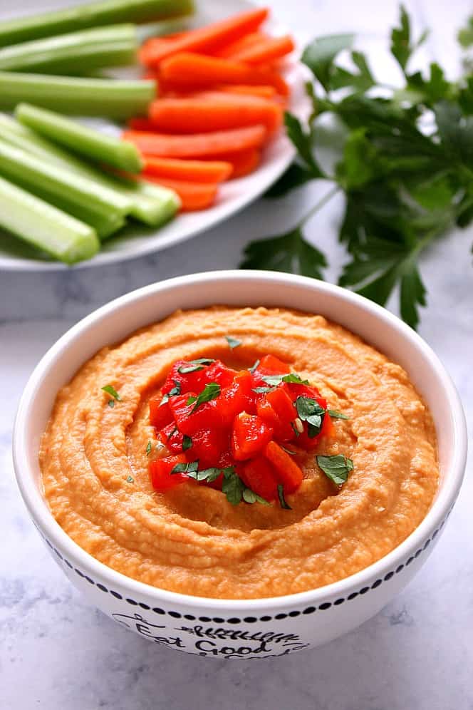 Red Pepper Hummus in a bowl, with chopped peppers on top.