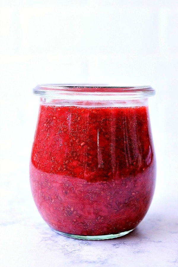 This sugar-free Easy Chia Jam takes only 10 minutes and 3 ingredients to make and can be made with any fruit you like! Perfect healthier jam with benefits of chia seeds. Side shot of strawberry jam in small glass jar.