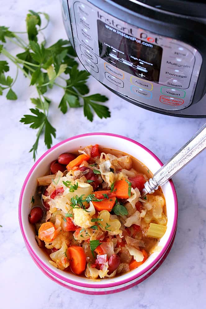 Overhead shot of bowl with vegetable soup, next to Instant Pot. 