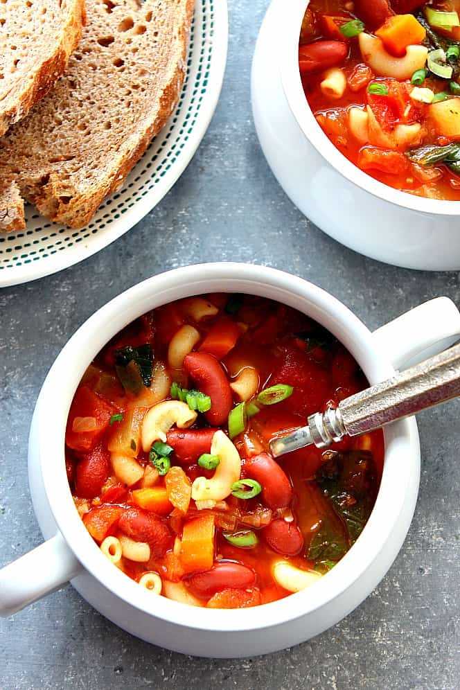 Overhead shot of bean and pasta soup in the soup bowls with handles.