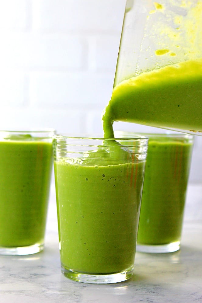 pouring green smoothie into glasses