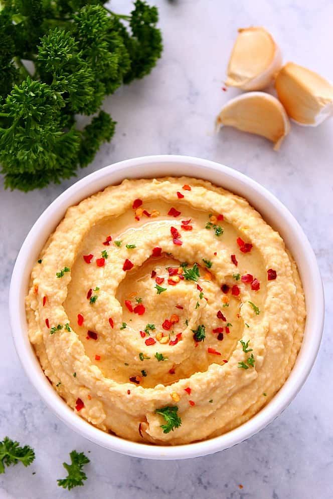 Hummus in a bowl set on a marble board.