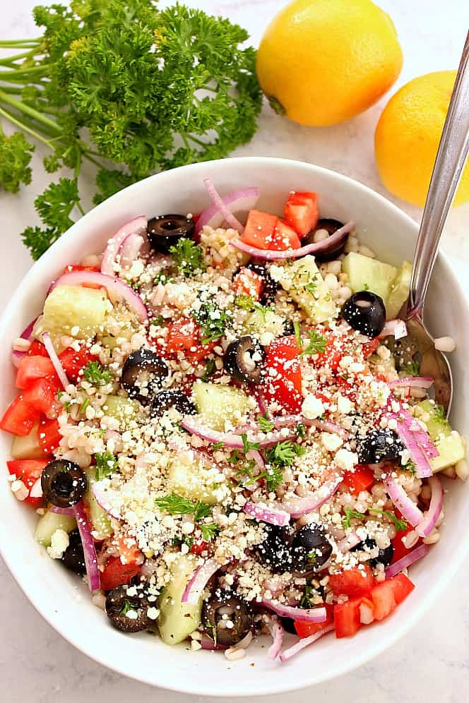 Greek Salad with Barley Recipe - fresh and bursting with flavor salad with Mediterranean flavors and barley. Great for meal prep! Greek salad in bowl with lemon and parsley