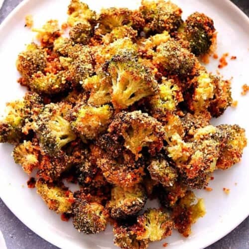 Square image of roasted broccoli on a white serving plate.