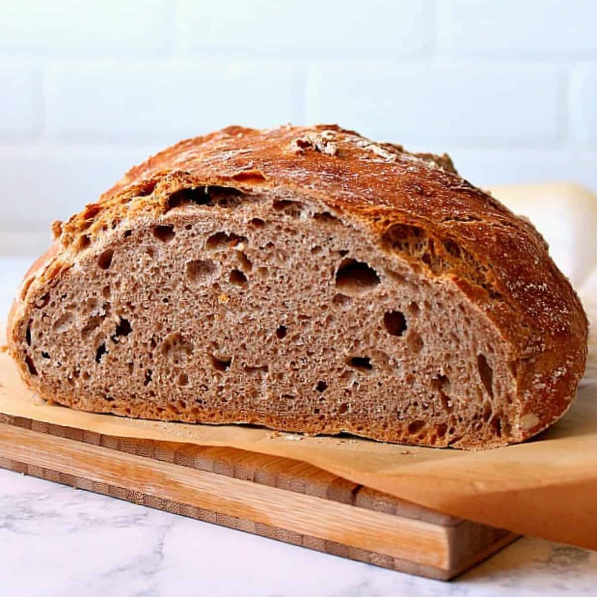 Whole wheat bread sliced on a board.