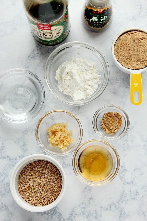 Teriyaki sauce ingredients in glass bowls and bottles on a marble board.