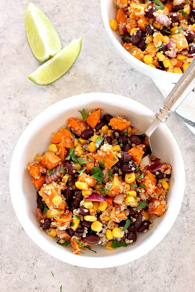 sweet potato quinoa salad in two bowls with lime wedges