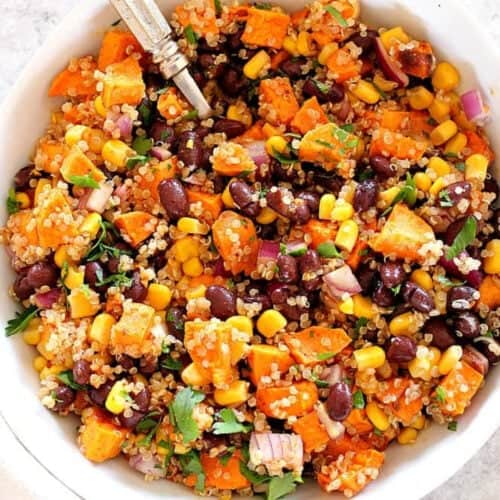 Sweet potato and quinoa salad in a white bowl with a fork.