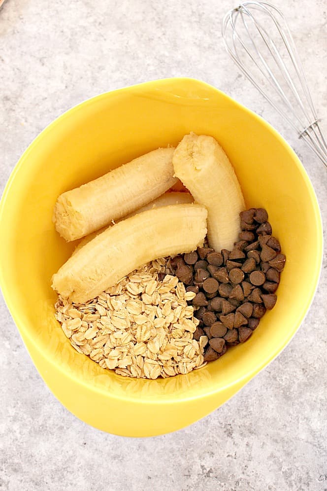 bananas, oats and chocolate chips in yellow mixing bowl