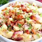 Potato salad in a white bowl with bacon.