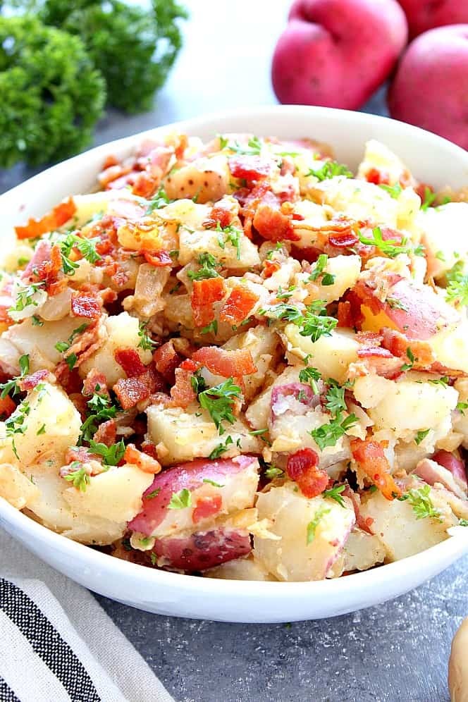 Close up of German Potato Salad with bacon, served in a white bowl. 