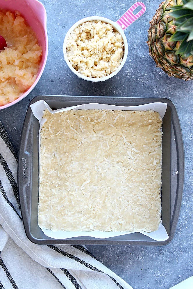 Crust pressed into the pan for crumb bars with pineapple filling. 