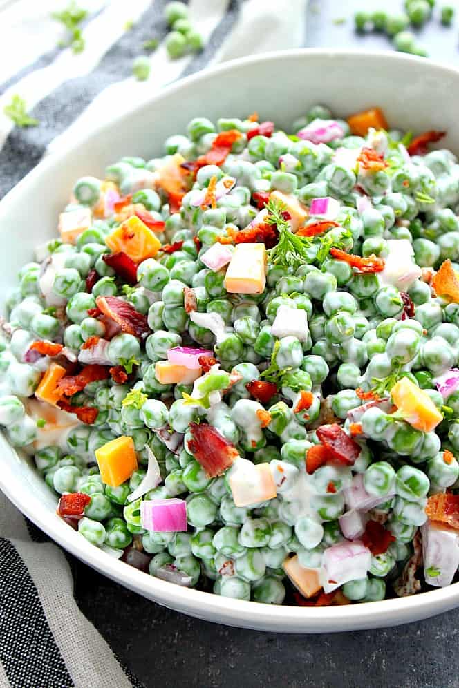 Green pea salad with cheddar and bacon served in white bowl. 