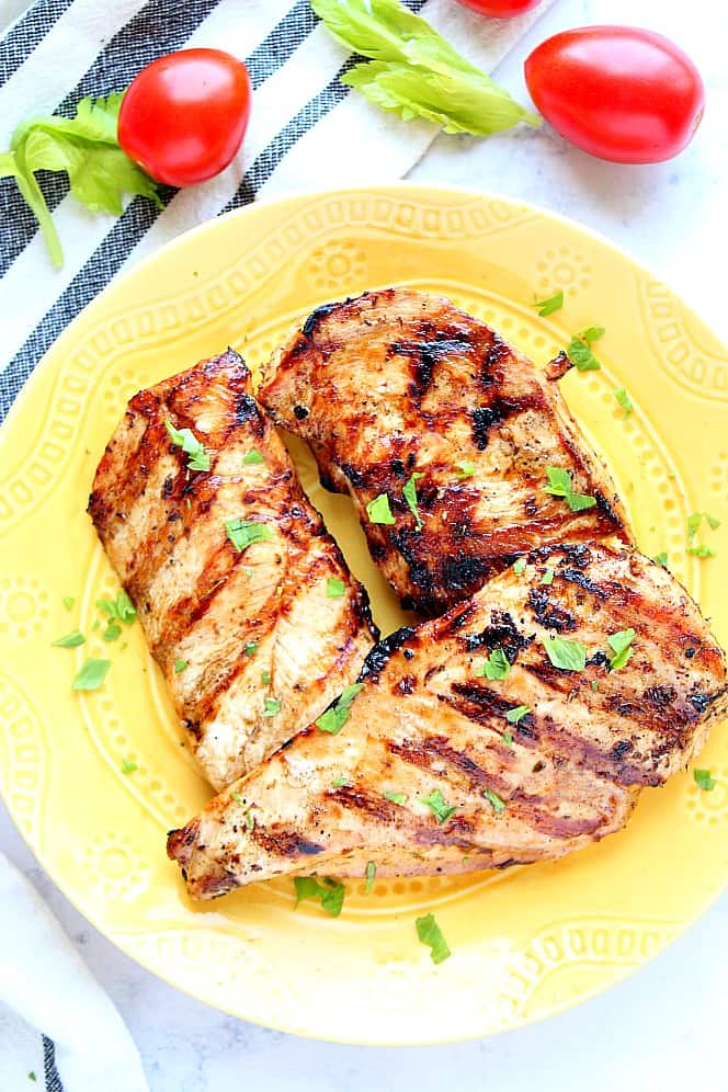 Overhead shot of easy grilled chicken on yellow serving plate with parsley garnish.