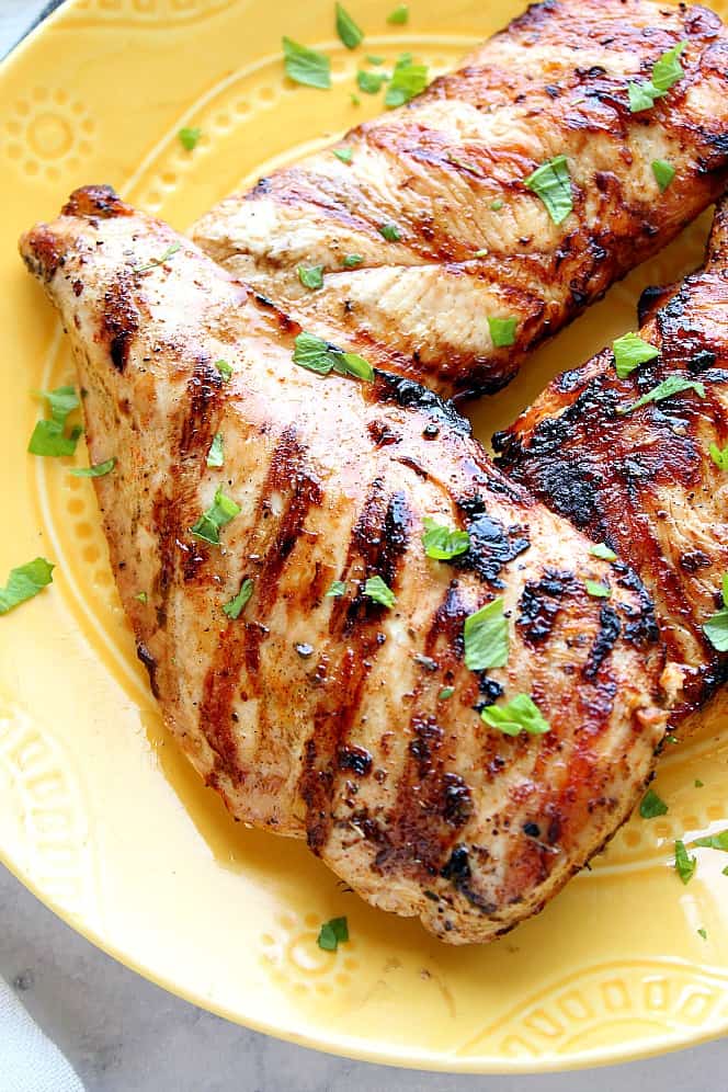 Close up of grilled chicken on yellow plate. 