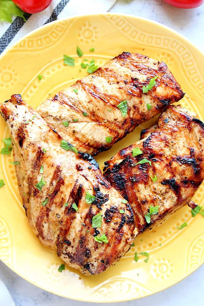 Overhead shot of grilled chicken breast on yellow plate. 
