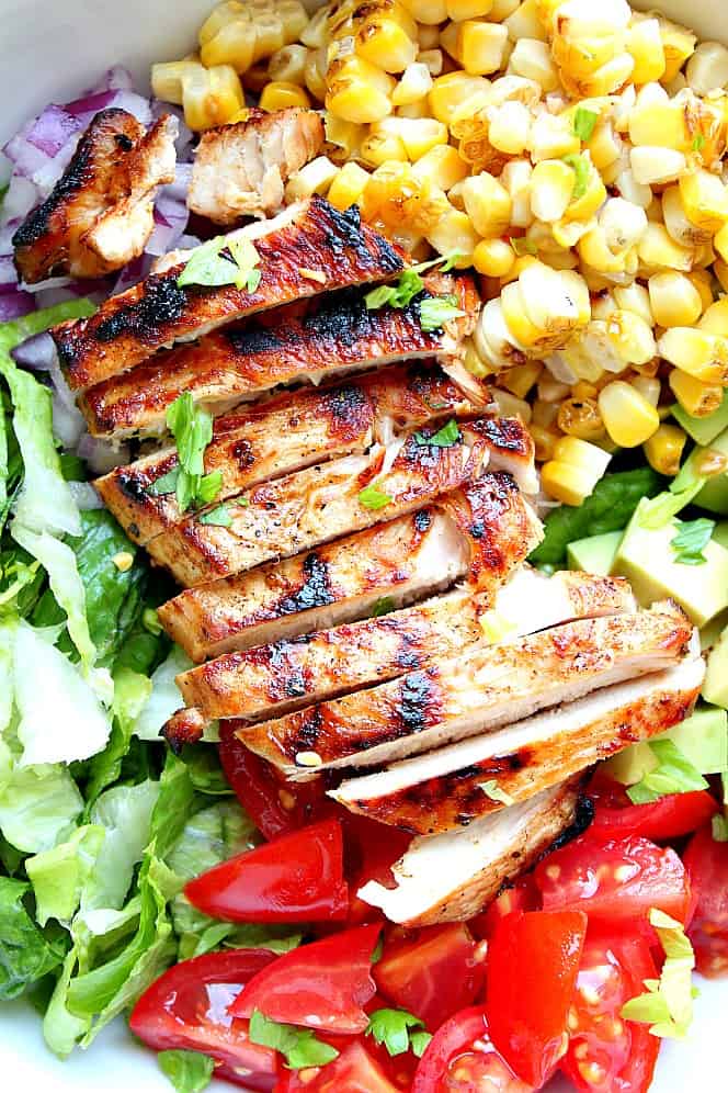 Close up shot of grilled chicken in a salad with corn.