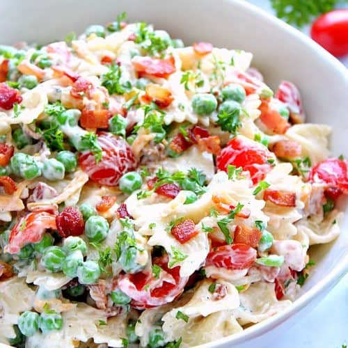 Pasta salad with bacon in a white bowl.
