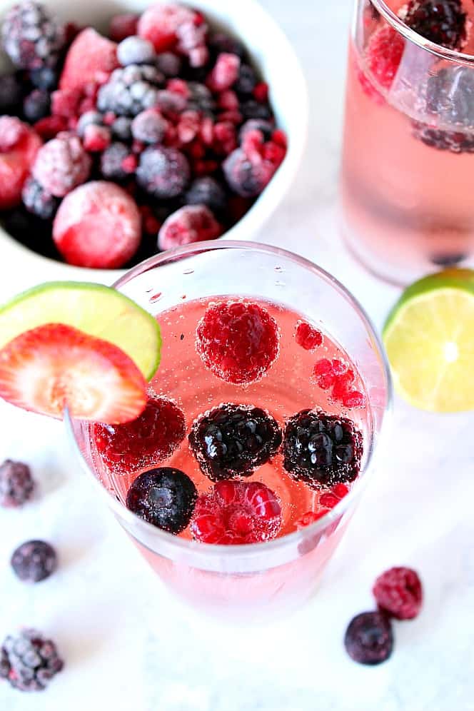 Overhead shot of berry sangria in glass with slice of strawberry and lime. 