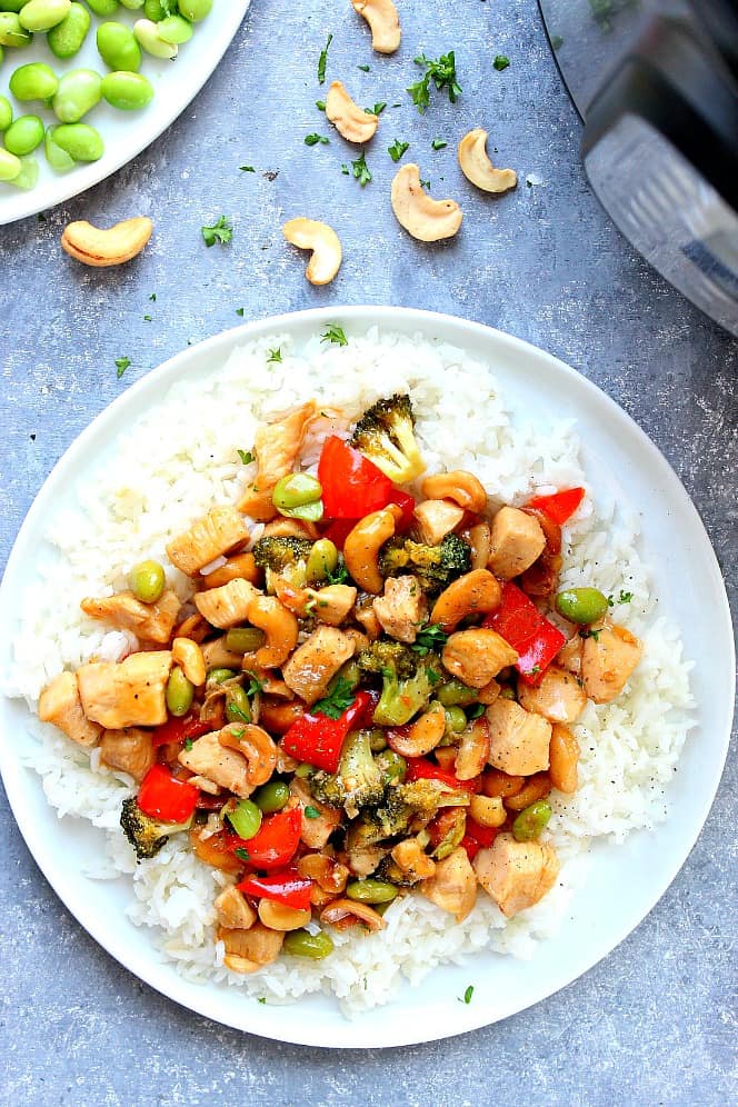 Overhead shot of Instant Pot Cashew Chicken on rice on white plate.