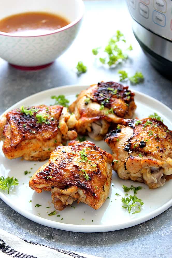 Side shot of roasted chicken thighs on white plate. 