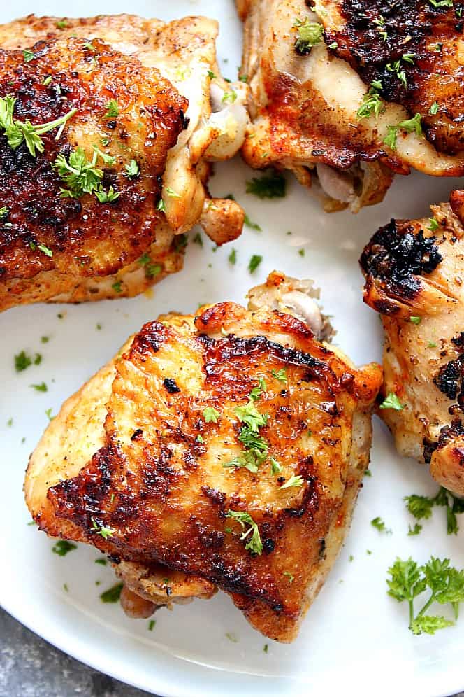 Overhead shot of roasted chicken thighs on white plate.