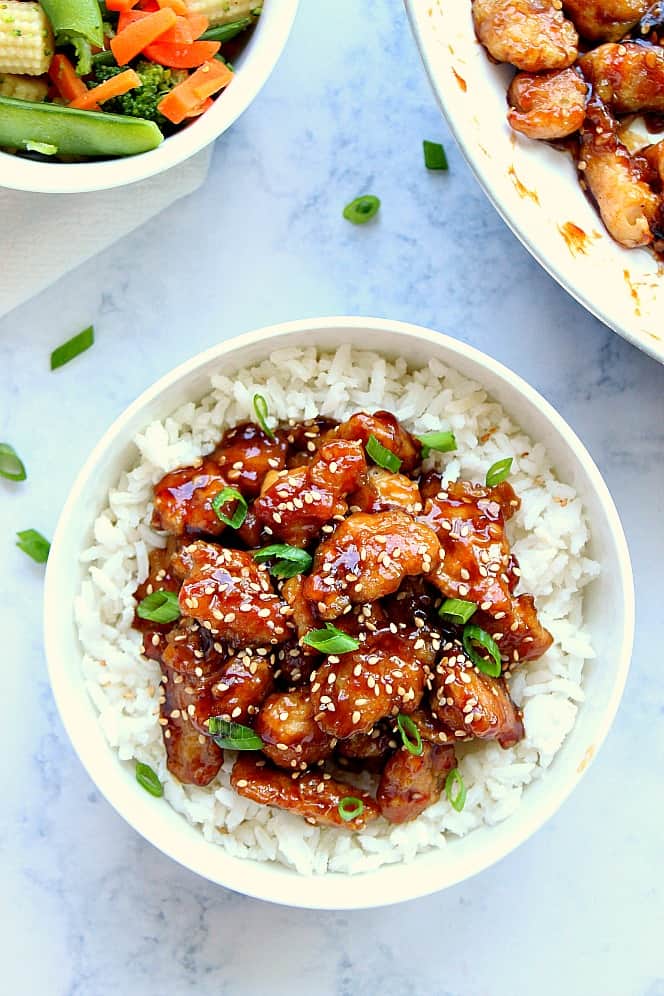 Overhead shot of Asian chicken on white rice with chopped green onions. 