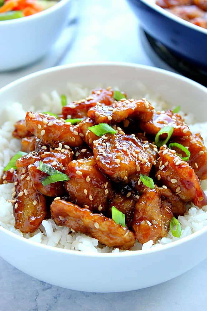 Side shot of chicken on white rice in a serving bowl. 