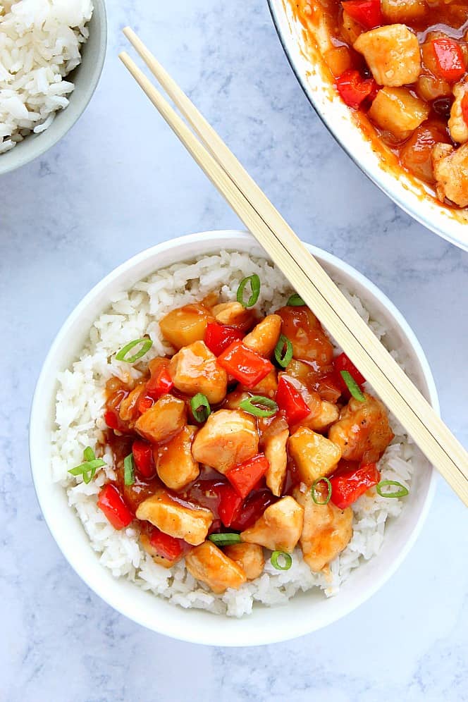 Chicken and peppers on top of rice in bowl.