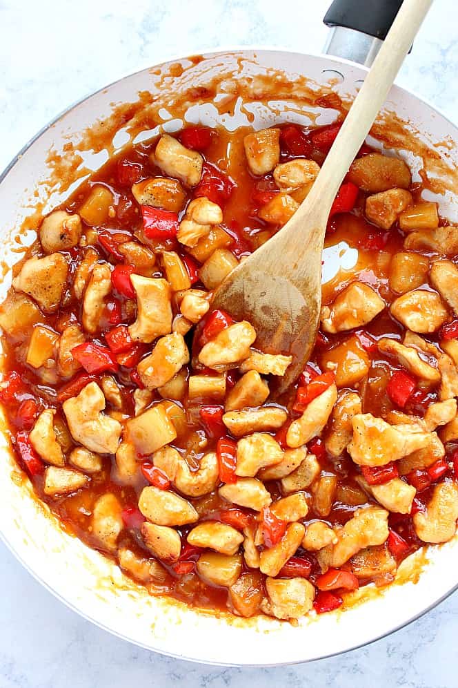 Sweet and sour chicken cooking in a pan.