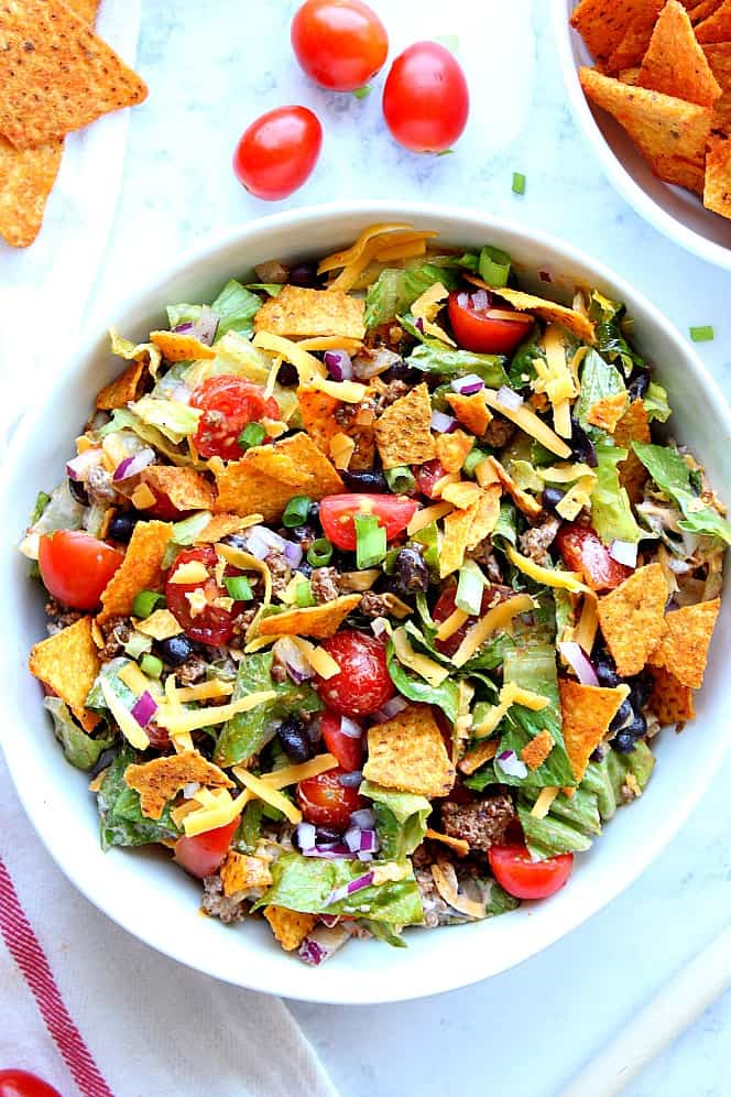 Overhead shot of taco salad with tortilla chips, tomatoes, cheese and beans.