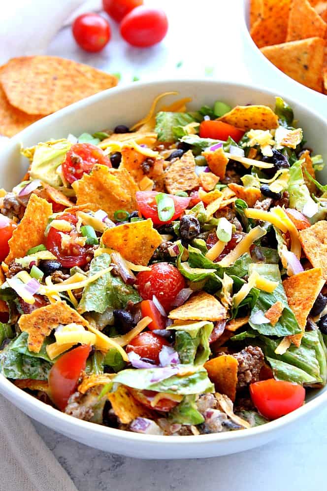 Side shot of Dorito taco salad with cheese tortilla chips, in white bowl. 