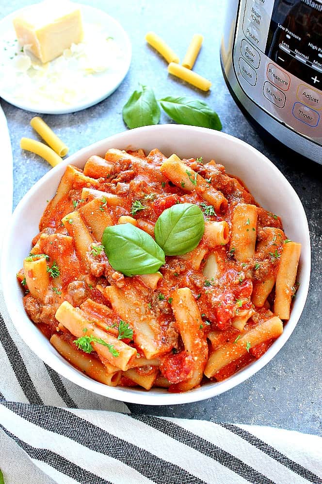 Side shot of ziti pasta in white pasta bowl next to Instant Pot. 