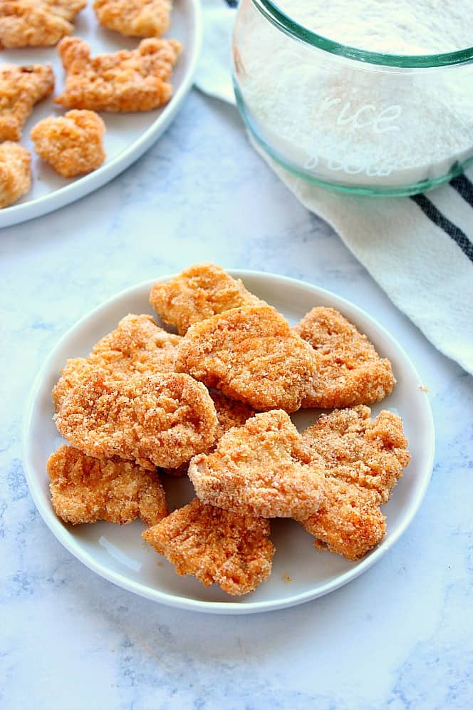 Side shot of chicken nuggets on white plate on marble background.