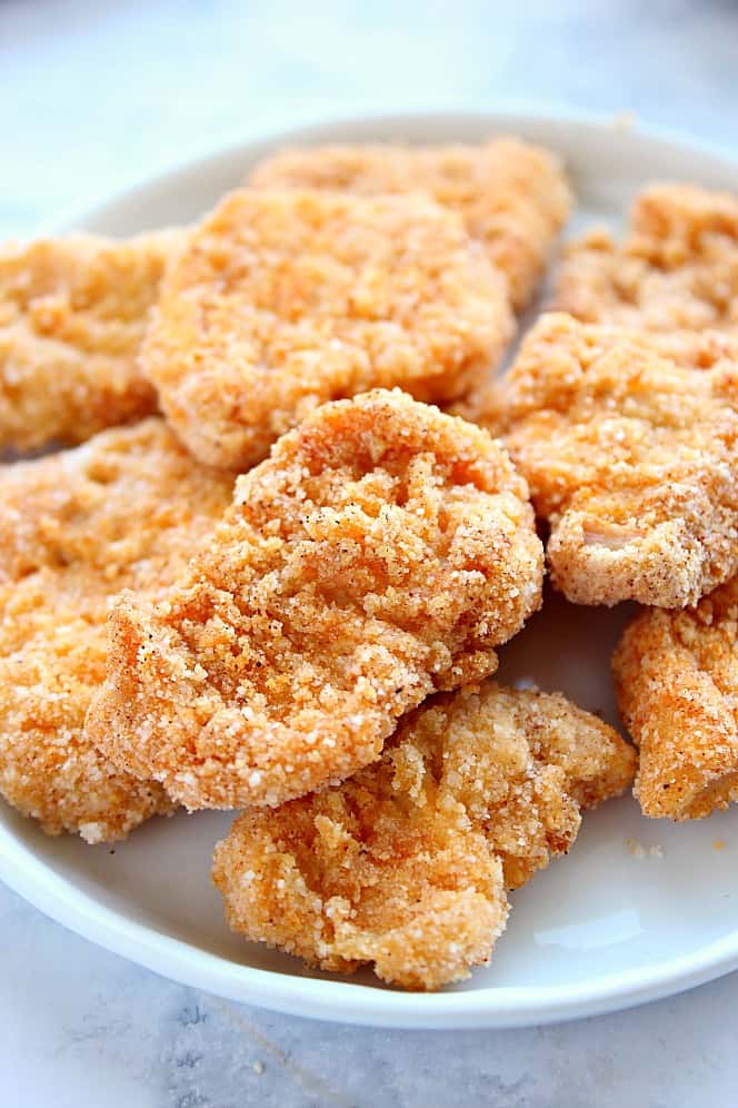 Side shot close up of gluten free chicken nuggets on white plate.