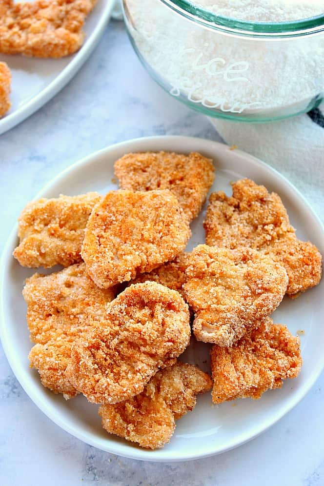 Overhead shot of chicken nuggets made with rice flour on white plate. 