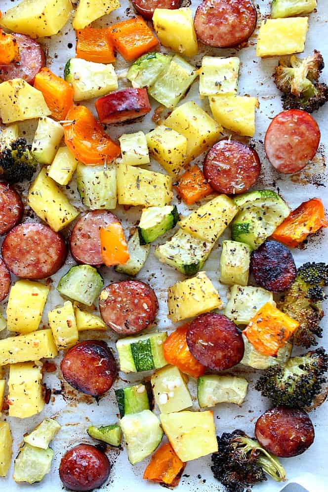 Overhead close up shot of roasted vegetables and sausage on sheet pan.