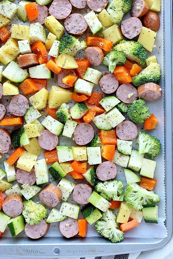 Overhead shot of baking pan with sausage, potatoes, broccoli, peppers and zucchini. 