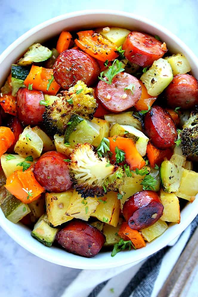 Overhead shot of roasted vegetables and sausage in white bowl. 