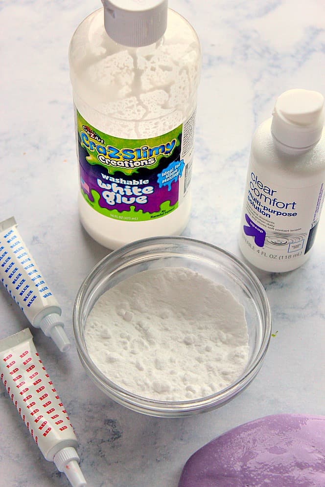 Overhead shot of ingredients needed to make slime: glue, baking soda in bowl and a bottle of all-purpose solution.