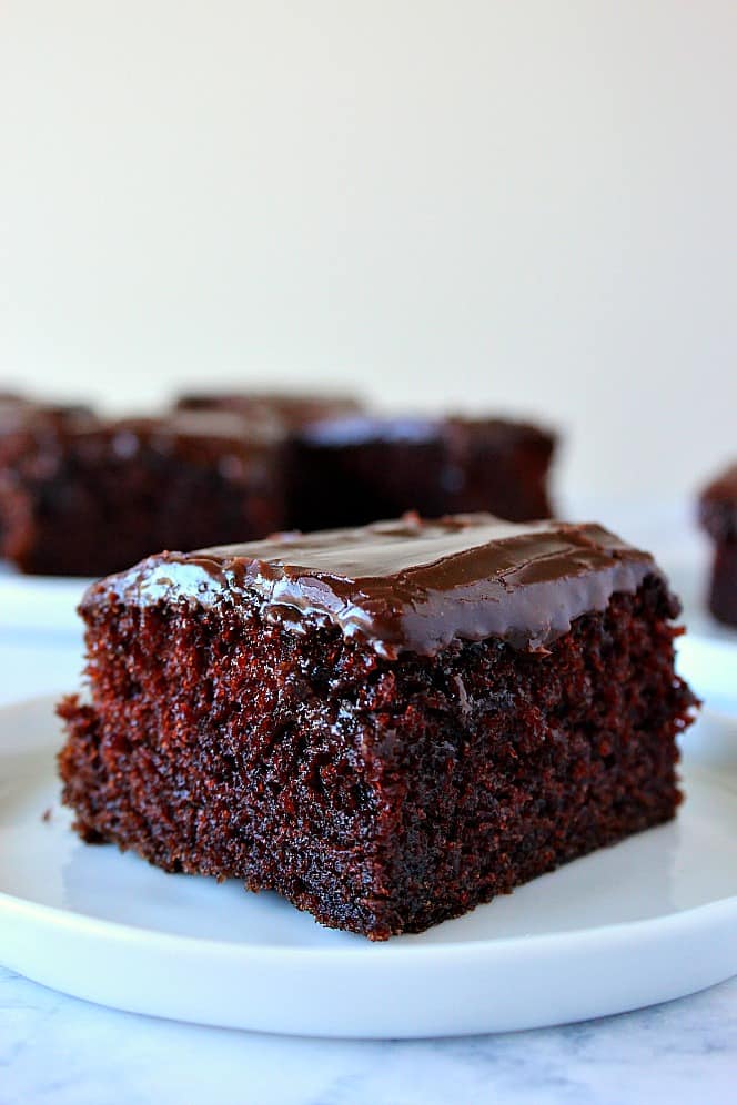 Moist chocolate cake square piece on white plate.