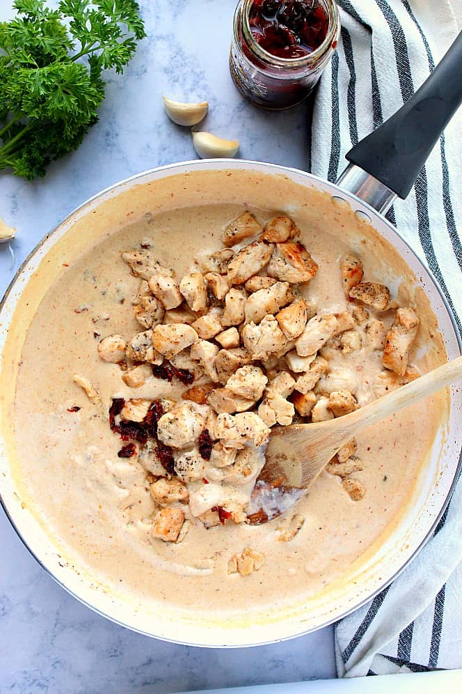 Overhead shot of creamy Alfredo sauce in skillet with cooked chicken. 