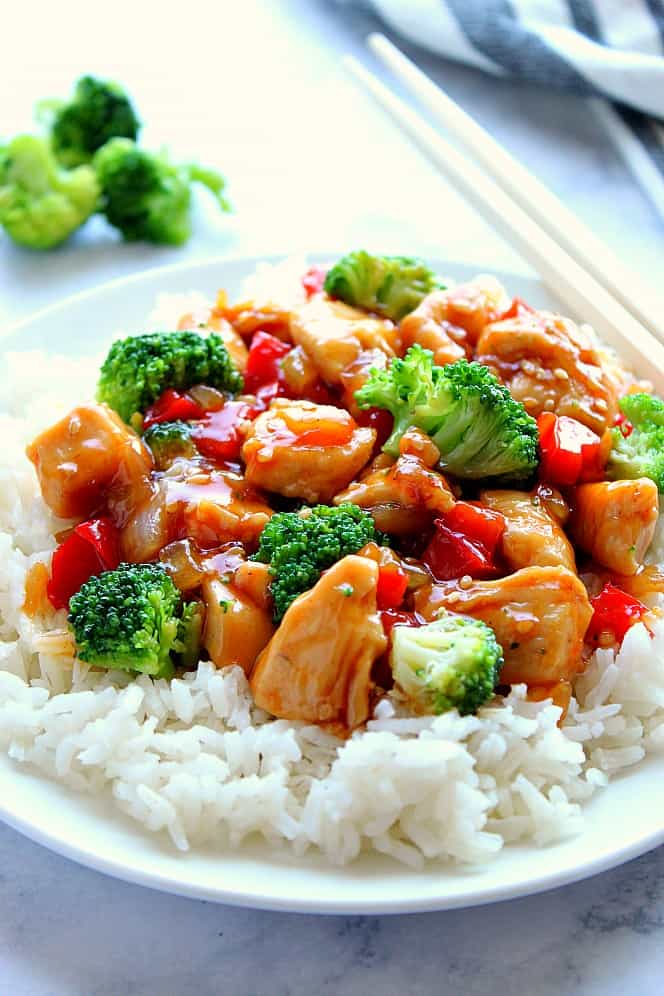 Side shot and close up of teriyaki chicken stir fry with broccoli on white rice on plate. 