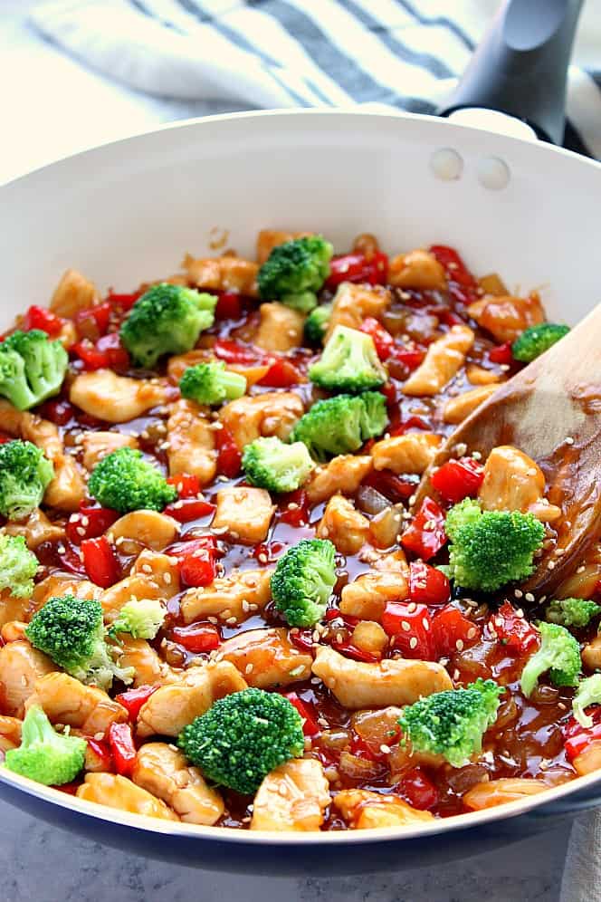 Side shot of white pan with rich teriyaki chicken, bell peppers and broccoli.
