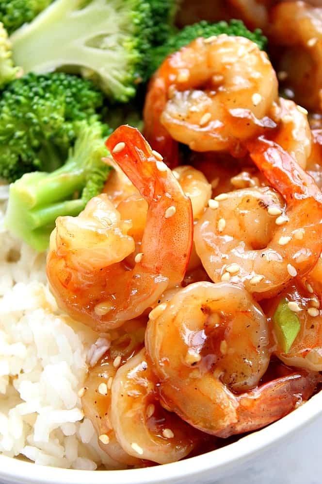 Close up on teriyaki shrimp with tails next to rice and broccoli. 