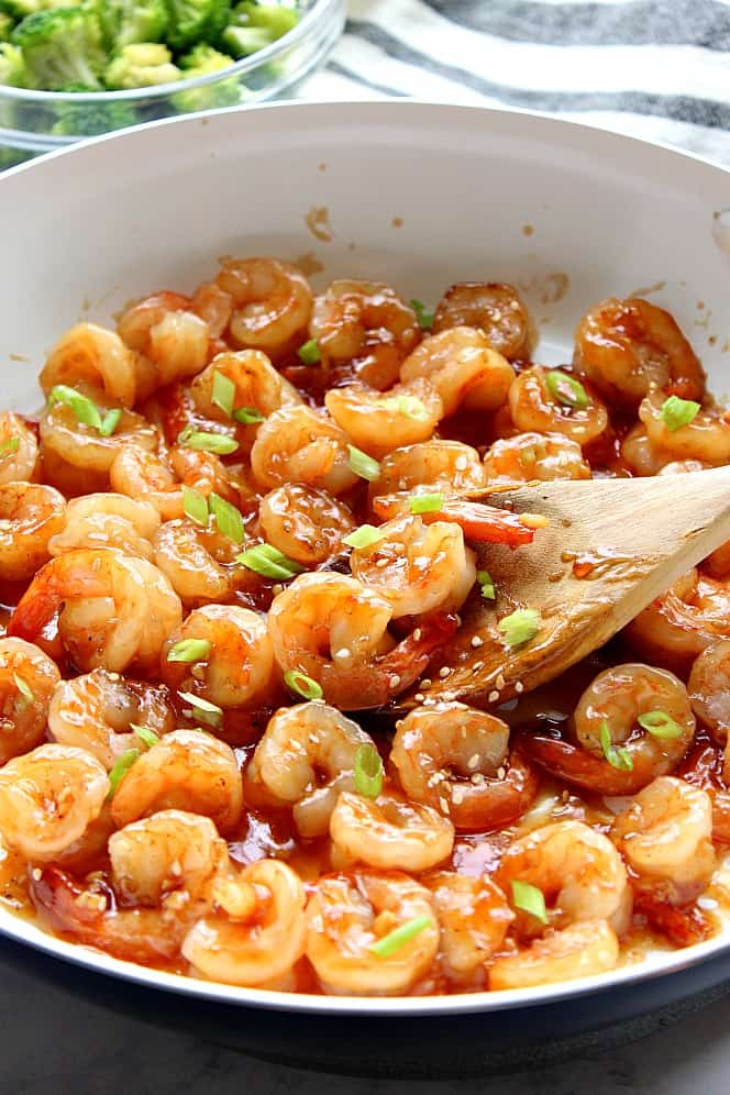 Side shot of teriyaki shrimp in white skillet. 