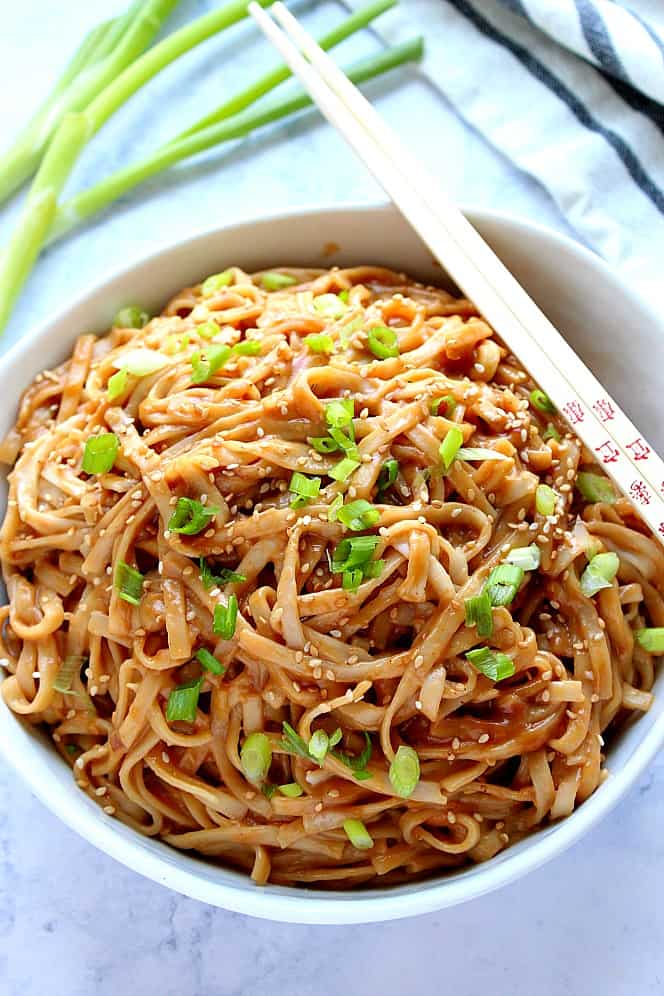 Overhead shot of big bowl of peanut noodles with green onions. 