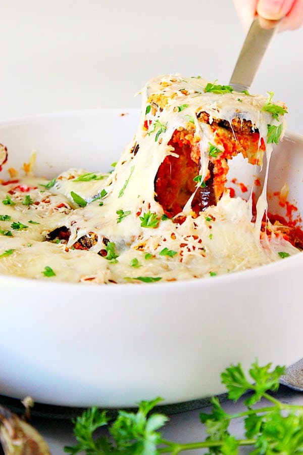 Baked Eggplant Parmesan Recipe - no mess, no fuss eggplant Parmesan with crispy garlic Parmesan breaded eggplant baked in the oven, not fried. Baked Eggplant Parmesan in white baking dish.