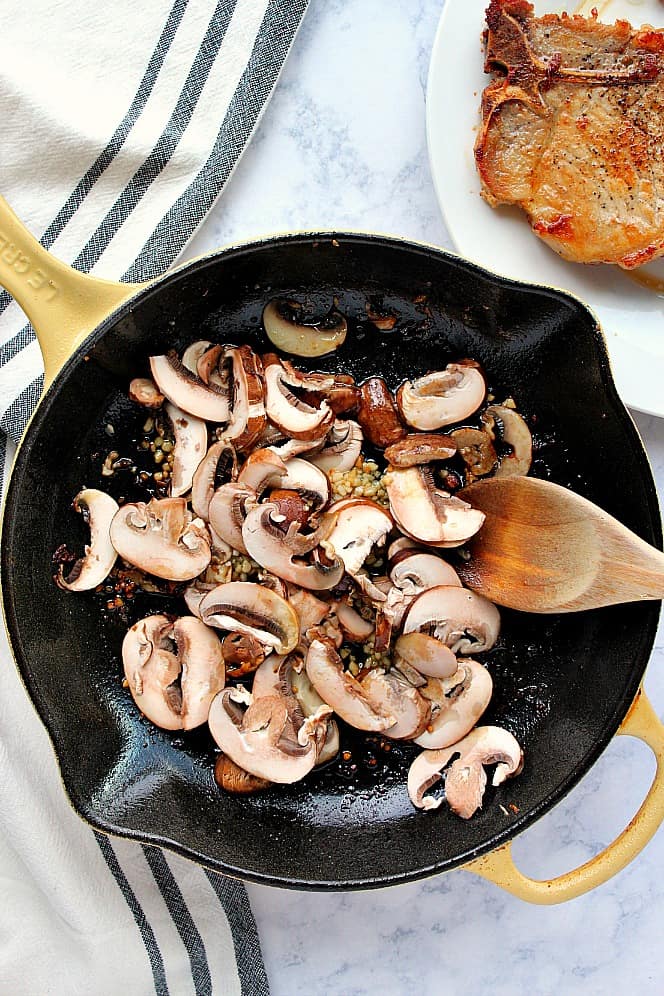 Overhead shot of mushrooms and garlic in cast iron skillet. 