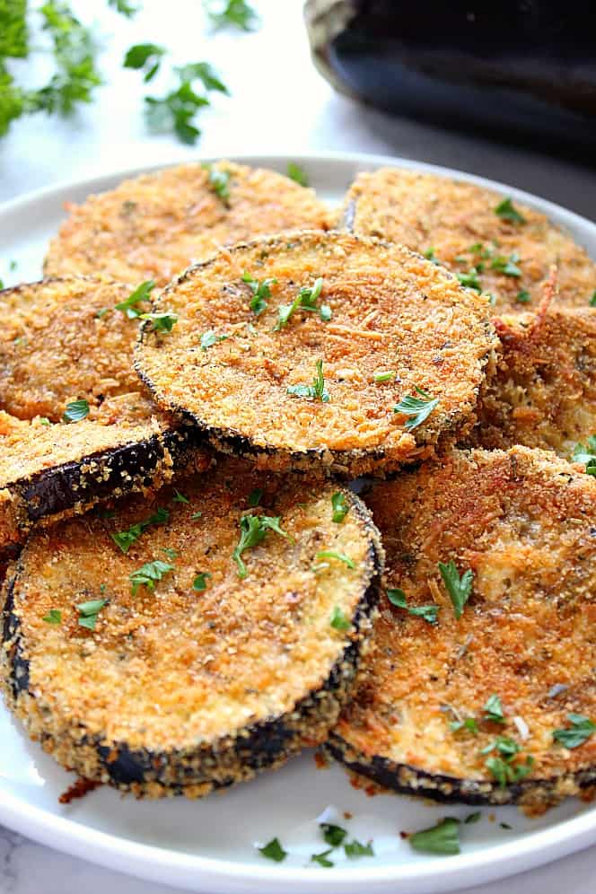 Side shot of baked crispy eggplant on white plate. 